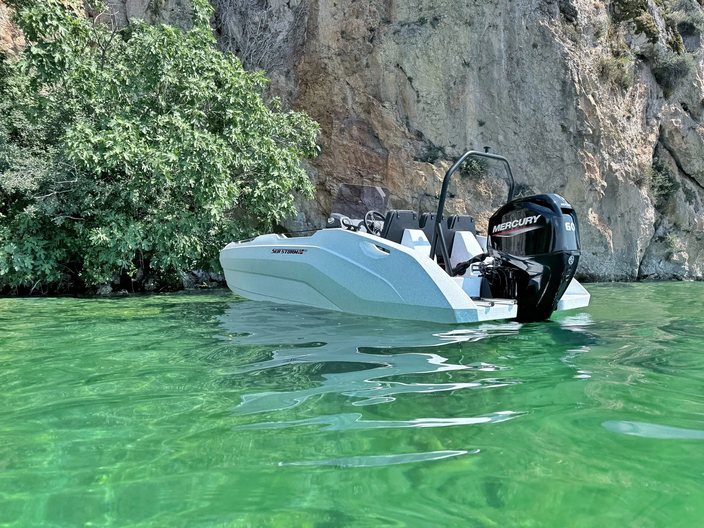 SeaStorm 17 in turquoise water below a rock face